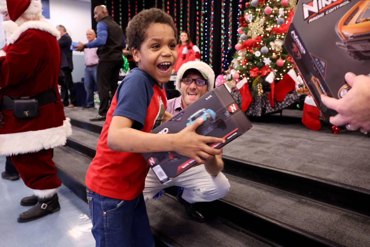 Jaciel Clark receives a toy during a holiday party at Sewell Elementary School in Henderson Fri ...