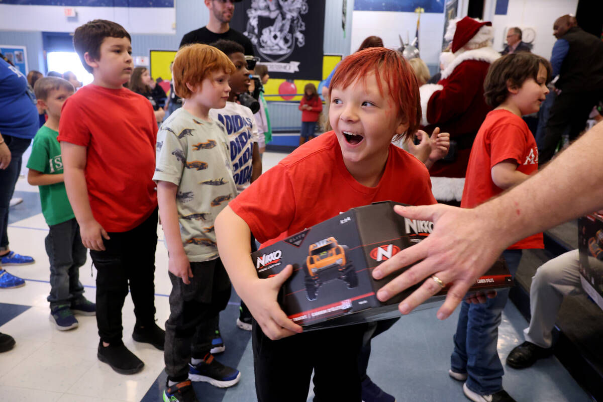 Troy Meik receives a toy during a holiday party at Sewell Elementary School in Henderson Friday ...