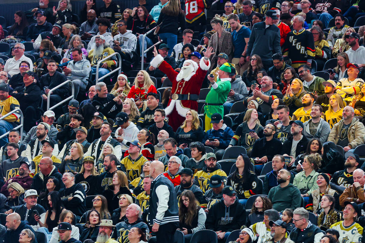 Santa Claus and one of his elves dance during an NHL hockey game between the Golden Knights and ...