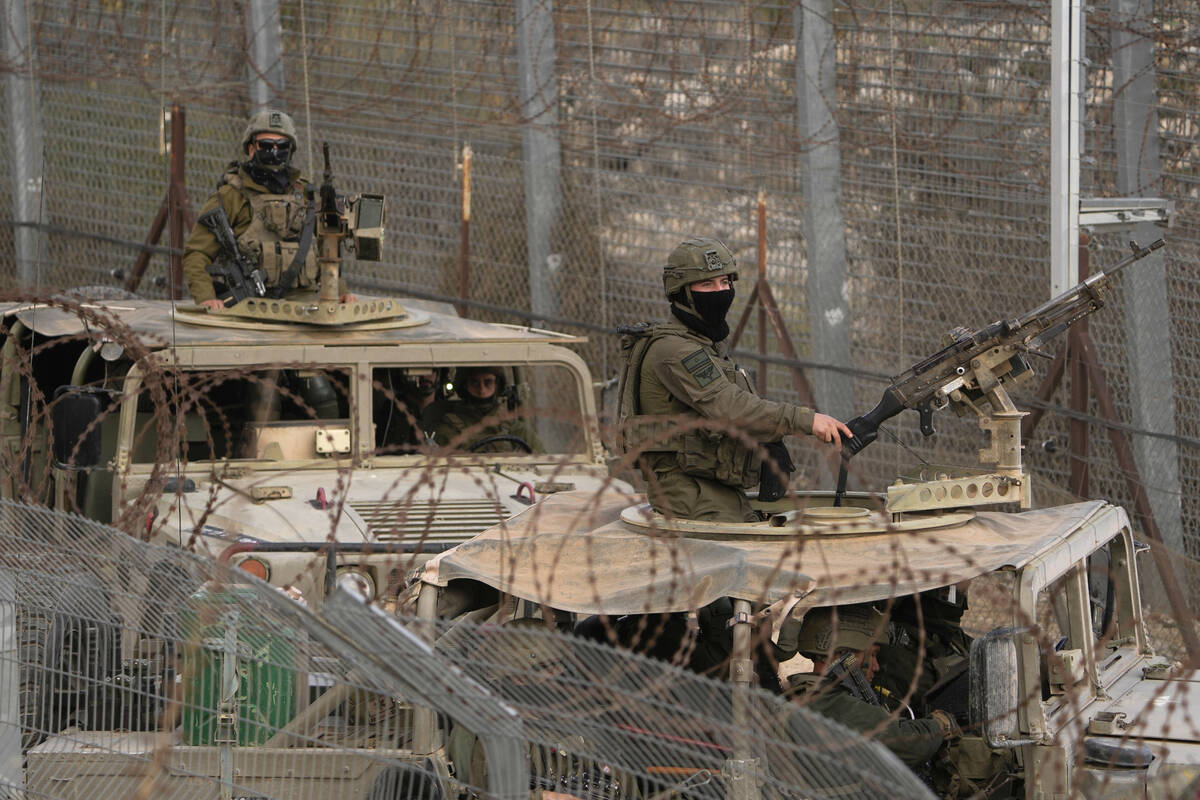 Israeli soldiers stand on armoured vehicles after crossing the security fence near the so-calle ...