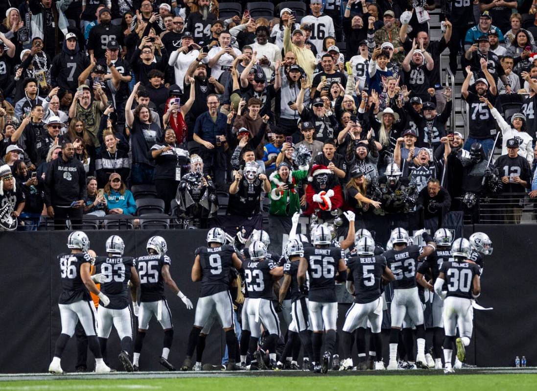 Raiders players celebrate with the ‘Black Hole’ fan area after recovering a fumbl ...