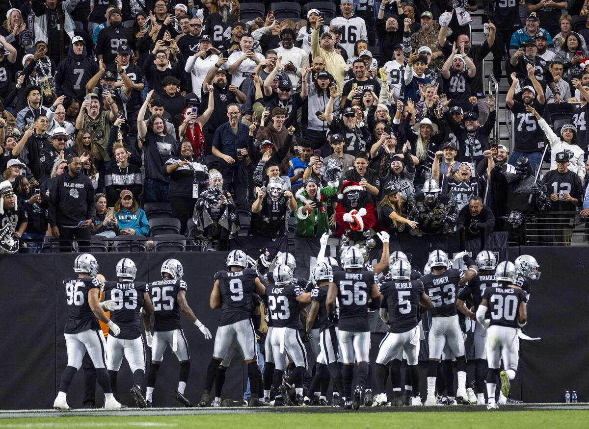 Raiders players celebrate with the ‘Black Hole’ fan area after recovering a fumbl ...