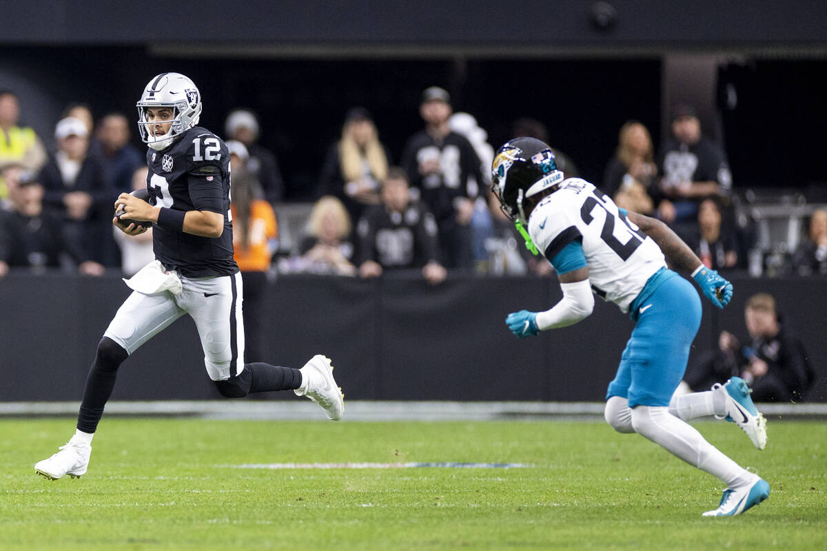 Raiders quarterback Aidan O'Connell (12) runs with the ball during the first half of the NFL ga ...