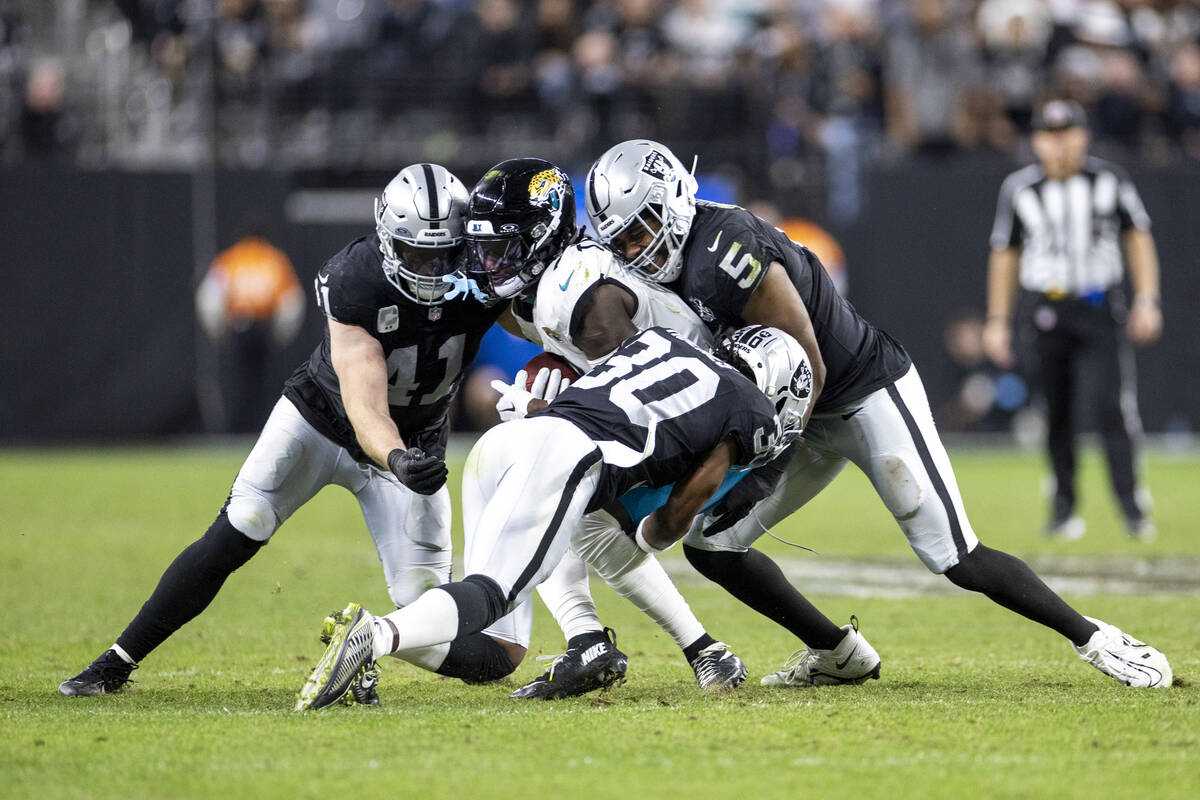 Raiders safety Tre'von Moehrig, center, is tackled by a group of Raiders during the second half ...