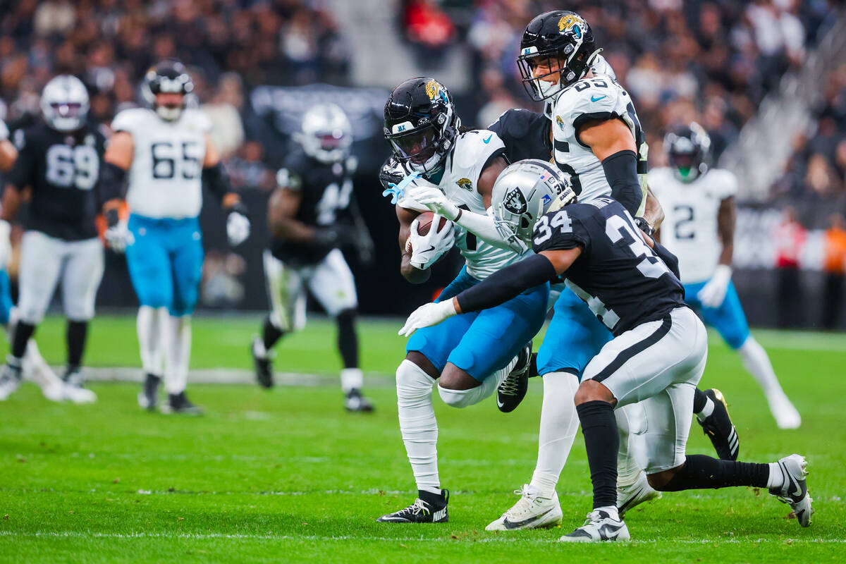 Jacksonville Jaguars wide receiver Brian Thomas Jr. (7) powers the ball past Raiders safety Tho ...