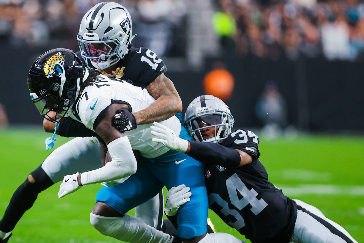 Raiders cornerback Jack Jones (18) and Raiders safety Thomas Harper (34) bring down Jacksonvill ...