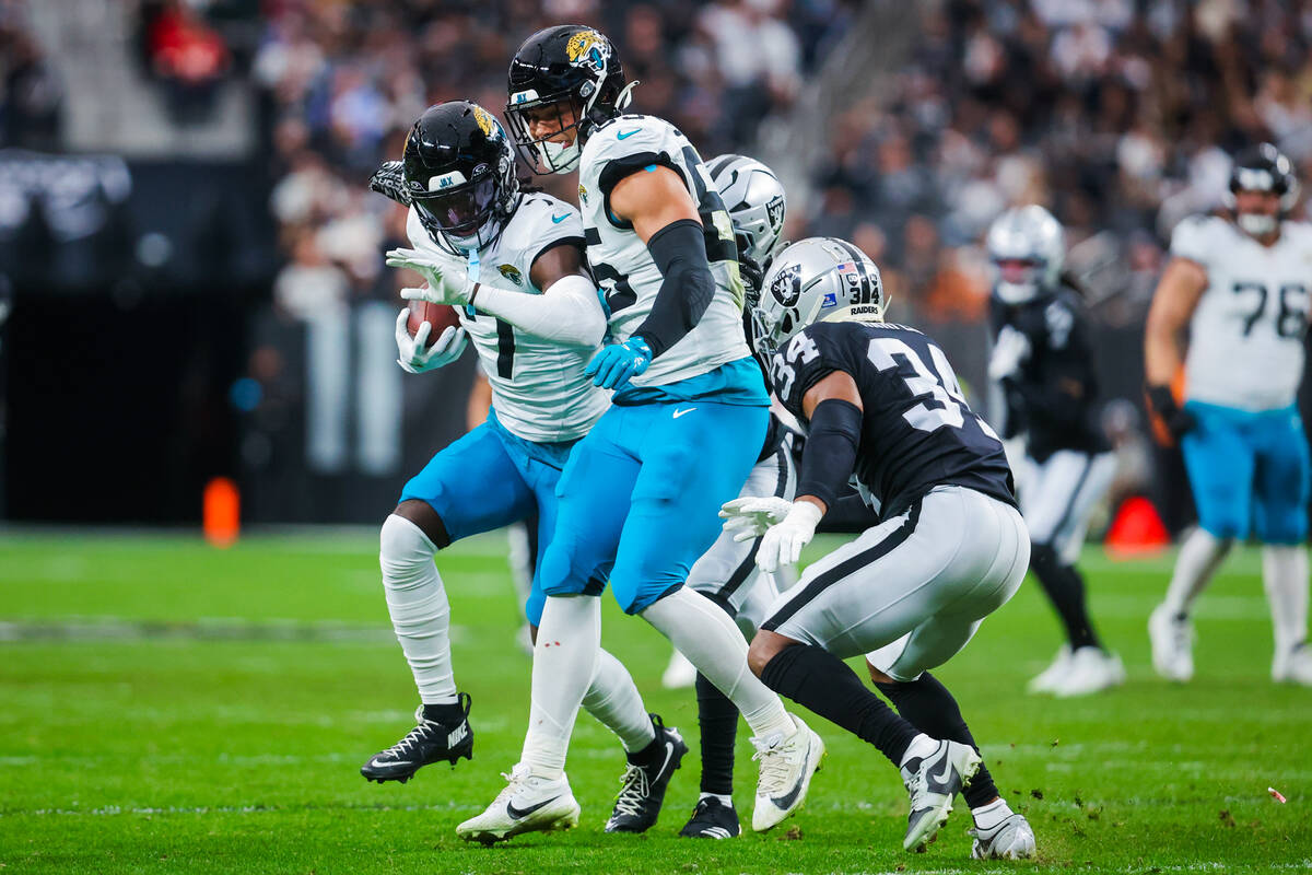 Jacksonville Jaguars wide receiver Brian Thomas Jr. (7) carries the ball past Raiders safety Th ...