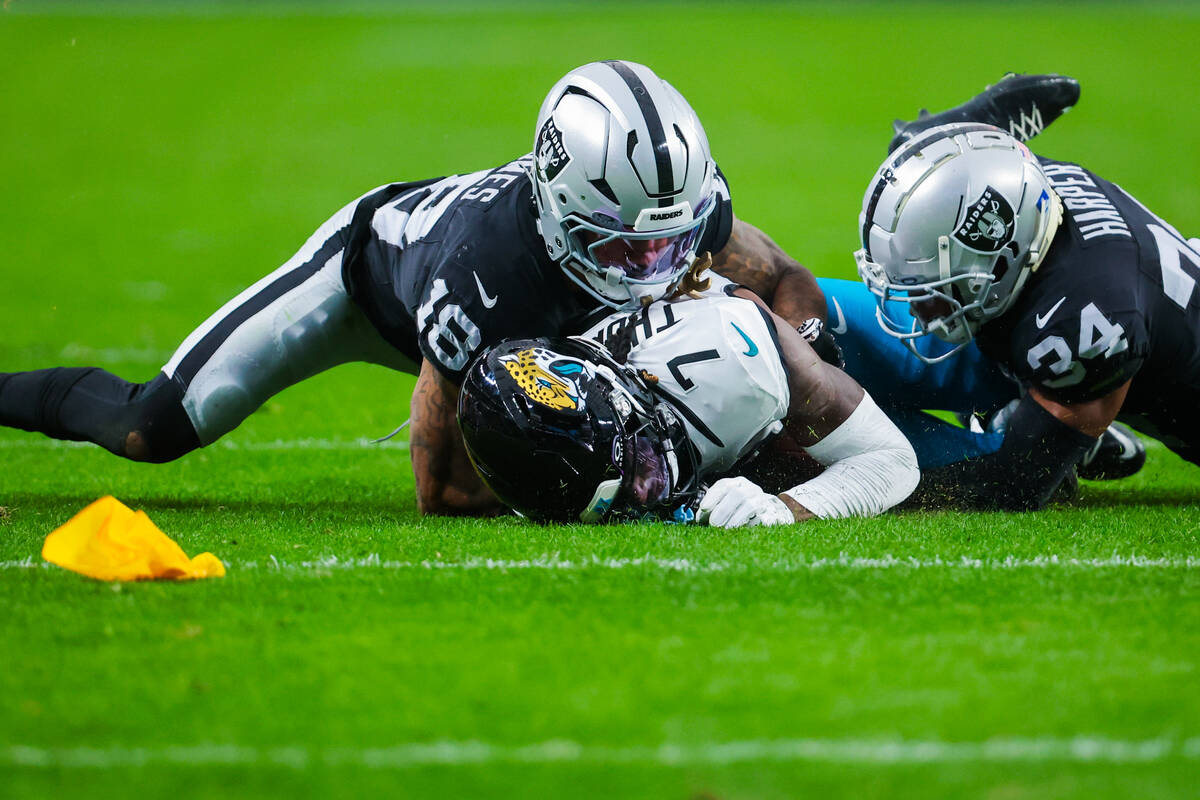 Raiders safety Thomas Harper (34) and Raiders cornerback Jack Jones (18) bring Jacksonville Jag ...