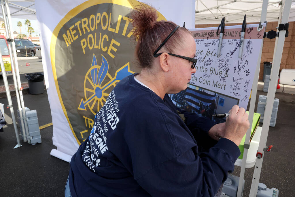 Christina Wilson, a first responder with MedicWest Ambulance, signs a banner honoring Metropoli ...