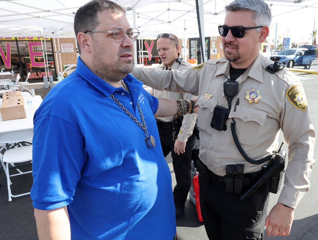 Neil Sackmary, owner of Nevada Coin Mart and Las Vegas police officer Joey Baraga comfort each ...