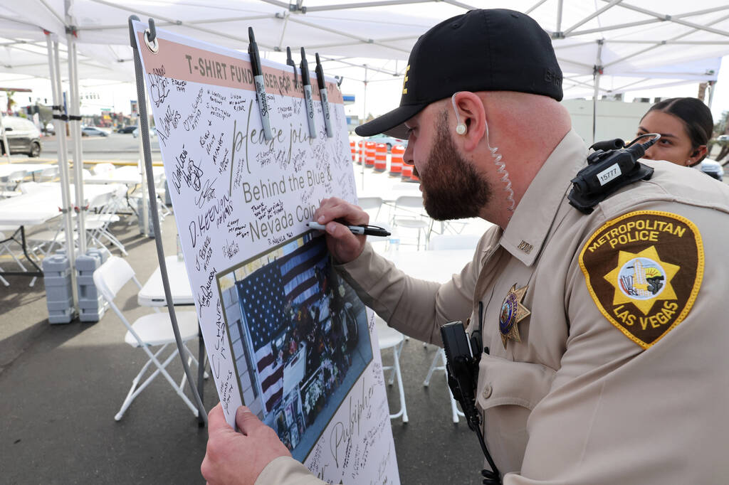 Las Vegas police officer Brian Brollini signs a banner honoring Metropolitan Police Department ...