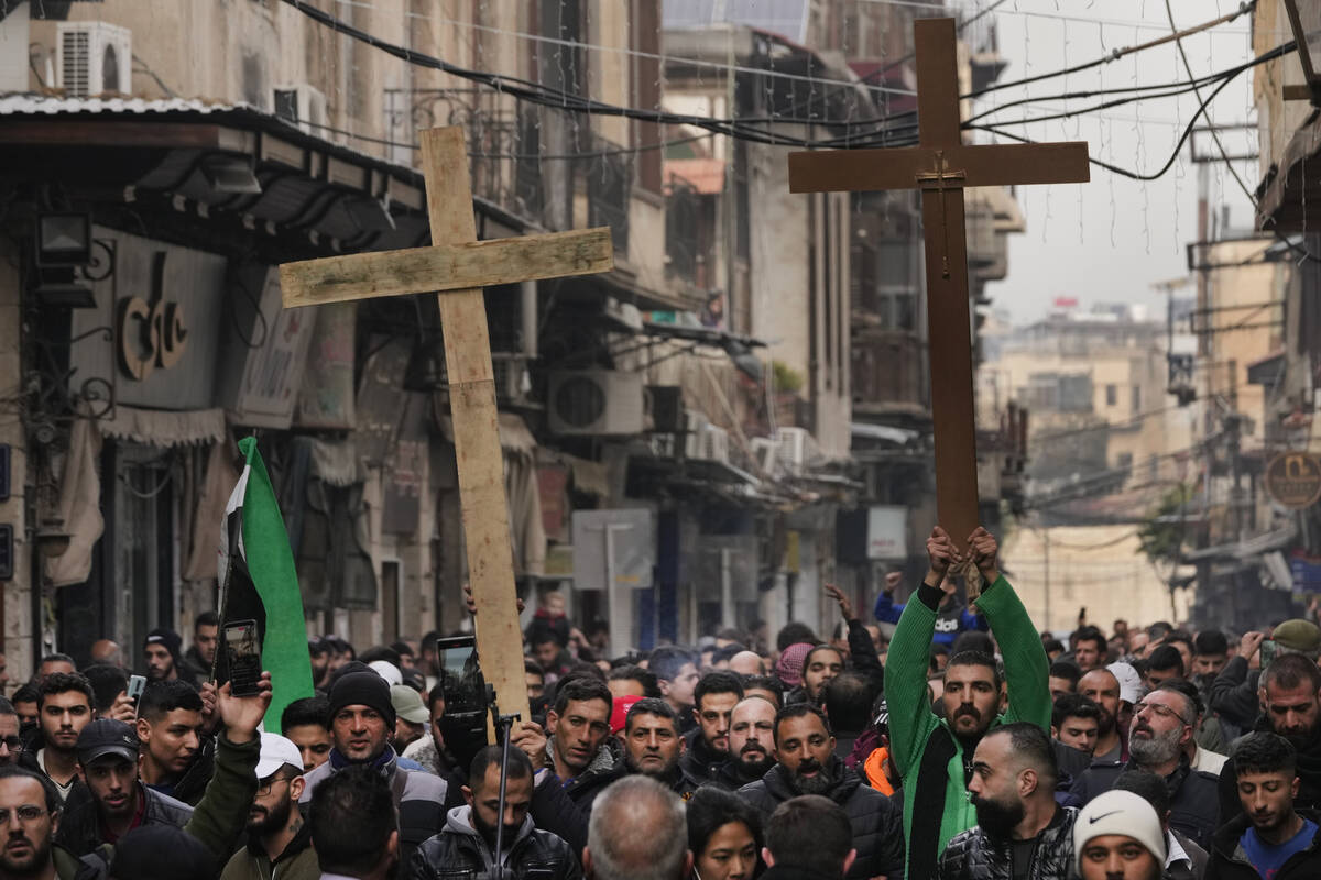 Syrian Christians hold up crosses and shout slogans in Damascus, Syria, Tuesday, Dec. 24, 2024 ...