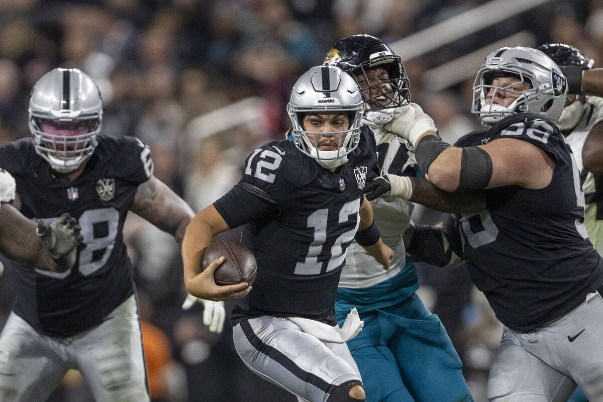 Raiders quarterback Aidan O'Connell (12) escapes pressure as guard Jackson Powers-Johnson (58) ...