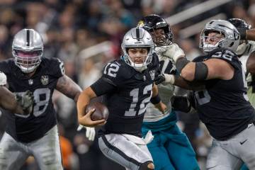 Raiders quarterback Aidan O'Connell (12) escapes pressure as guard Jackson Powers-Johnson (58) ...