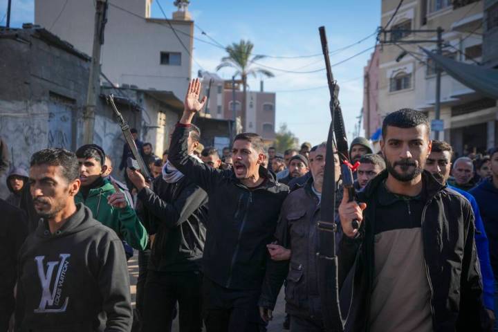 Relatives and neighbors, two of them holding guns, walk during the funeral procession of a vict ...