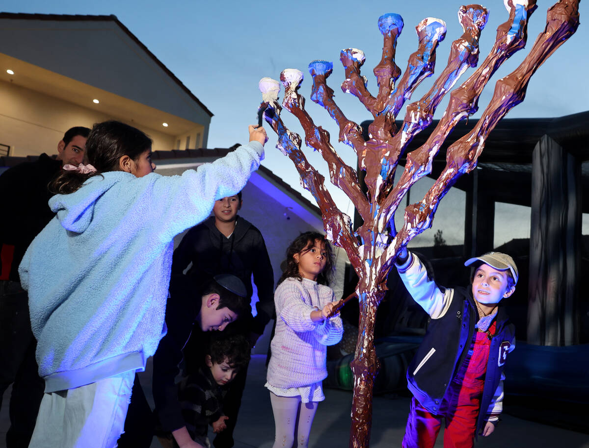 Children, including Aviel Nathan, 7, right, cover the menorah with chocolate during a lighting ...