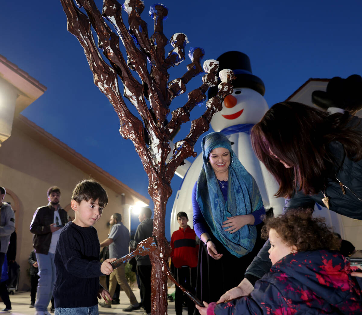 Children cover the menorah with chocolate during a lighting celebration on the first night of H ...