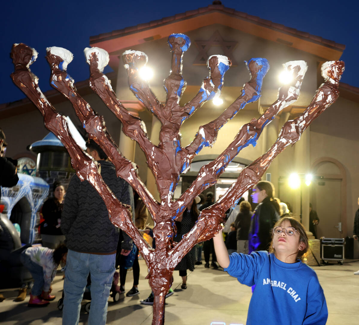 Children cover the menorah with chocolate during a lighting celebration on the first night of H ...