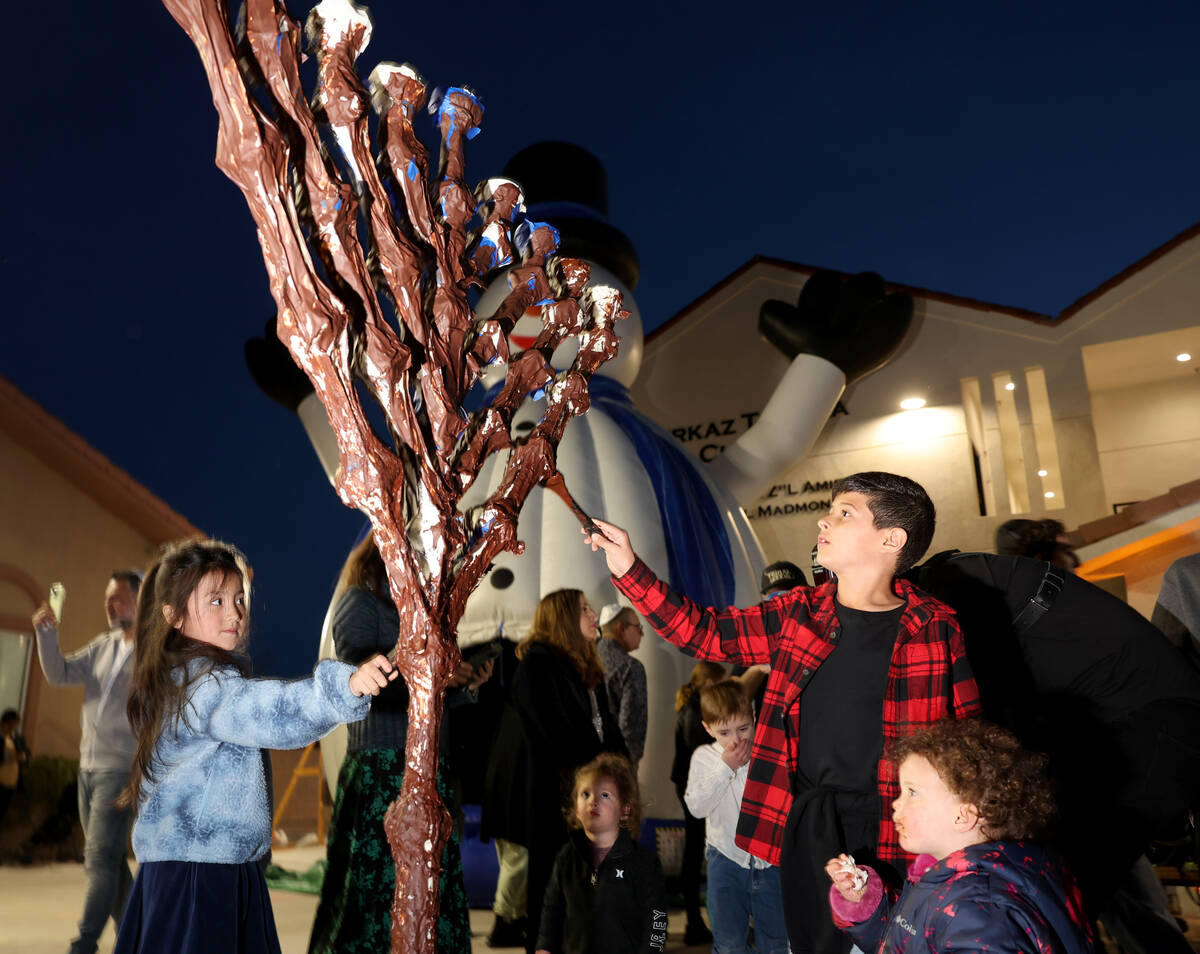 Children cover the menorah with chocolate during a lighting celebration on the first night of H ...