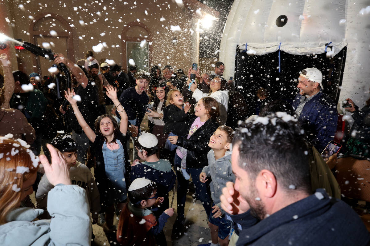 Children dance under a “snowfall” during a menorah lighting celebration on the fi ...