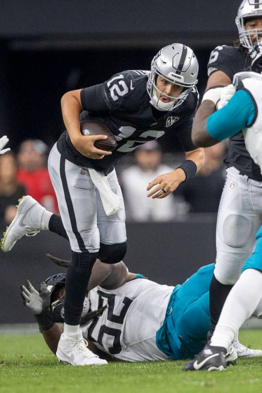 Raiders quarterback Aidan O'Connell (12) avoids a tackle from Jacksonville Jaguars defensive ta ...