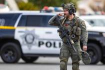 A Metropolitan Police Department SWAT officer walks down the street as police take a barricaded ...