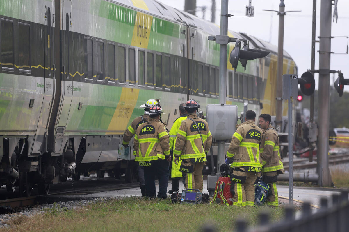 Firemen gather after Brightline train collided with a fire truck in downtown Delray Beach, Fla. ...