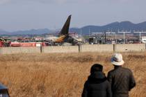 People watch as firefighters and rescue team members work at Muan International Airport in Muan ...