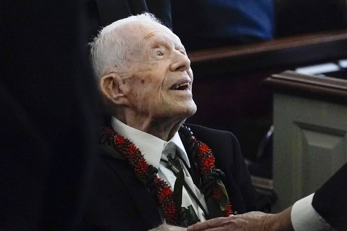 FILE - Former President Jimmy Carter greets attendees as he departs the funeral service for his ...