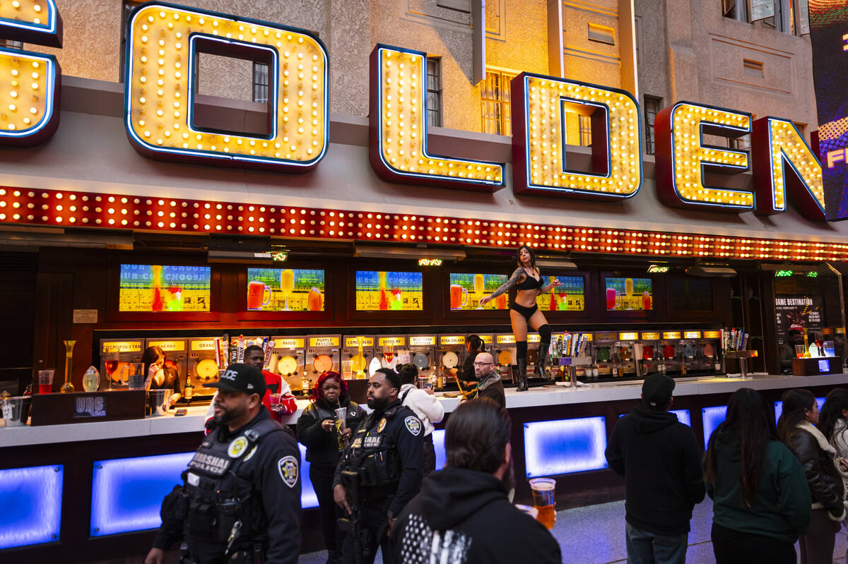 A dancer performs on the bartop as Las Vegas police marshals walk by while New Year's Eve revel ...