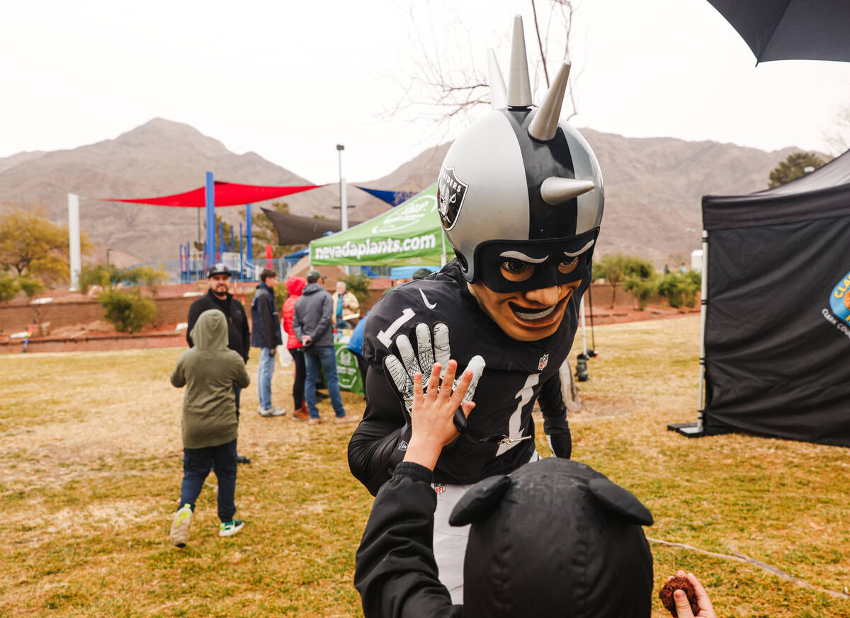 Raider Rusher, mascot for the Raiders, high-fives a child at a “Green Week” event where par ...