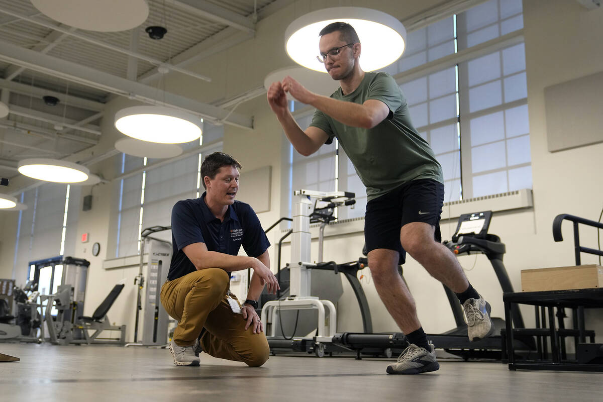 Physical therapist Tyler Detmer, left, works with patient Jacob Bullard at WashU, Monday, Dec. ...