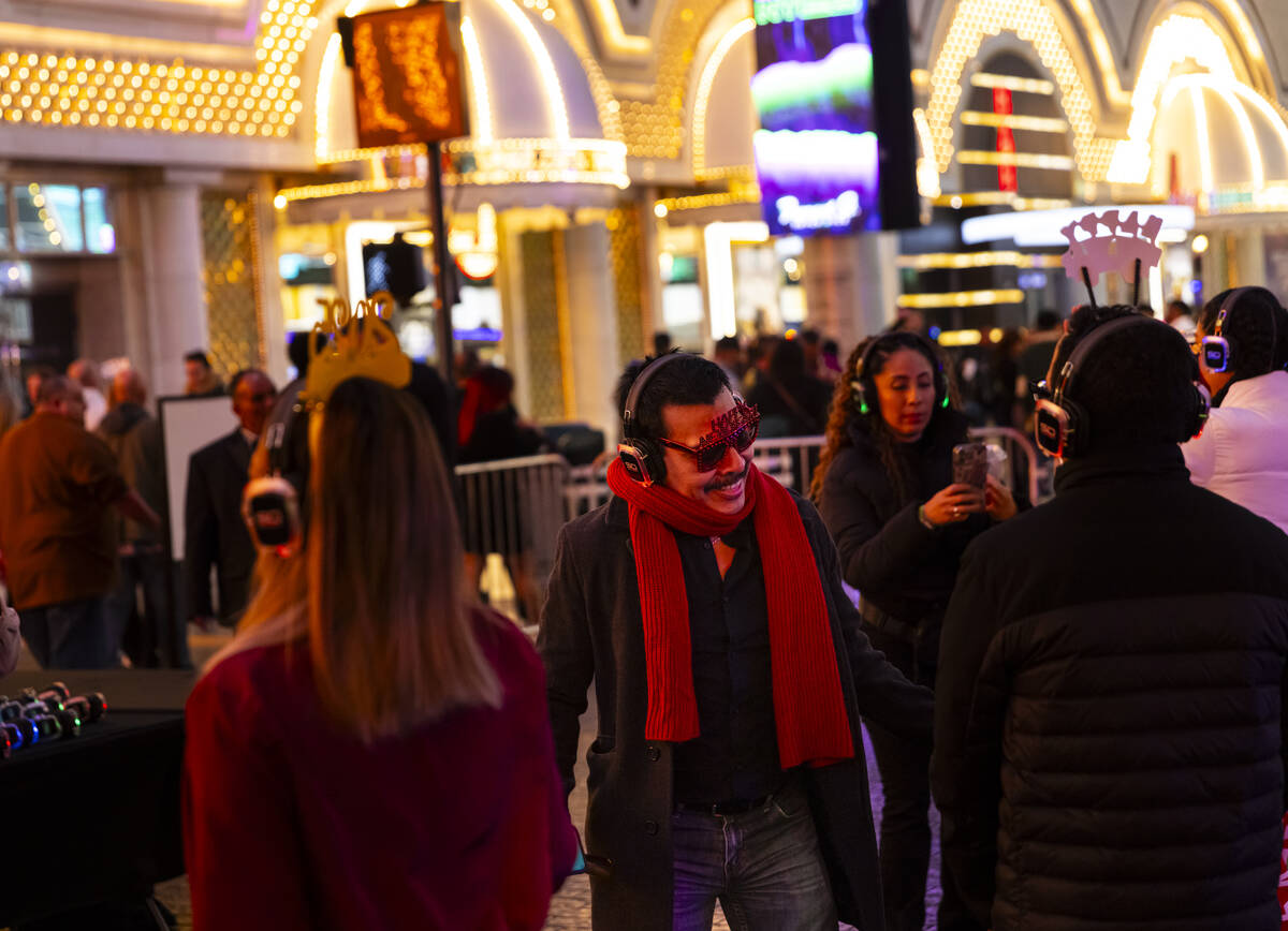 People dance to a silent disco party during the New Year's Eve celebration at the Fremont Stree ...