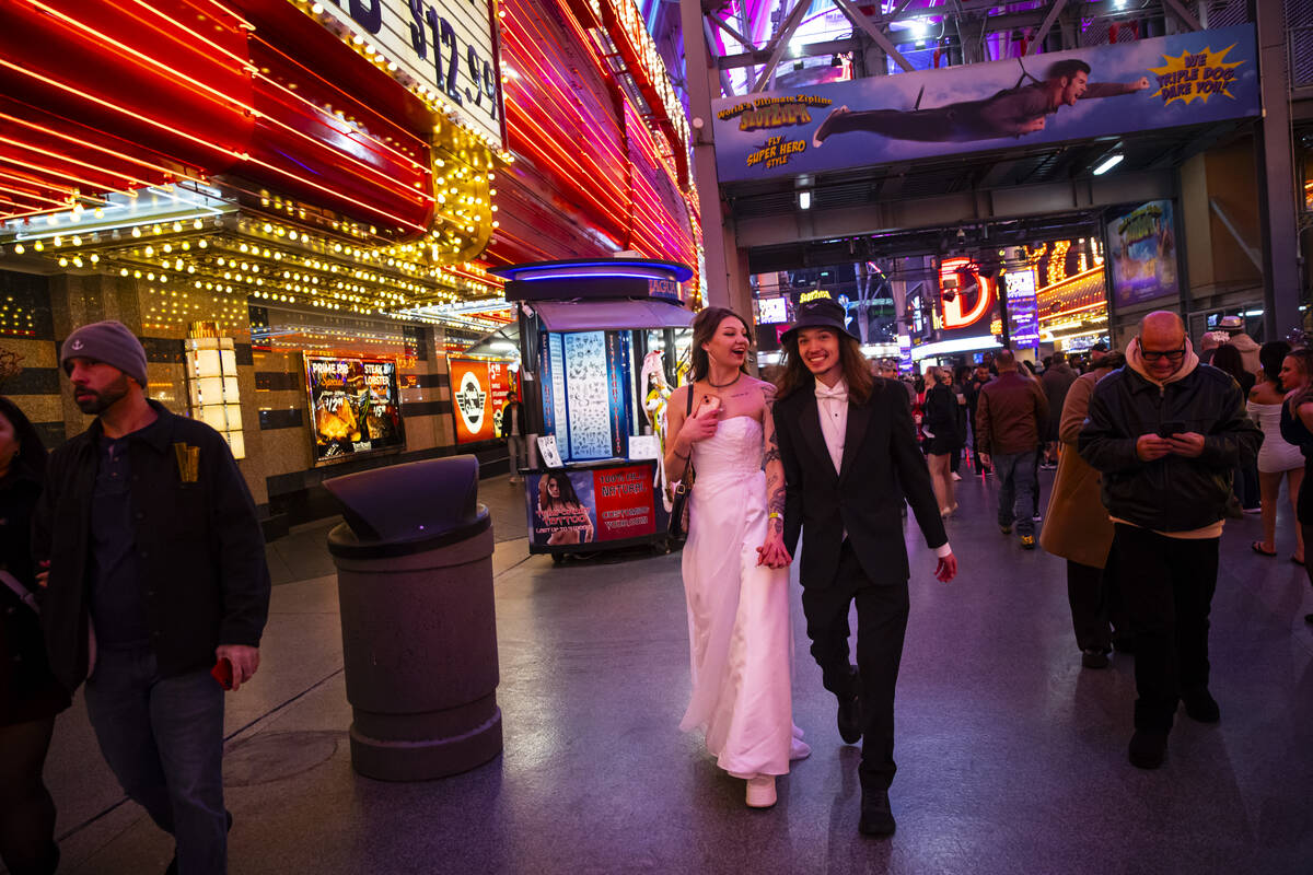 Newlyweds Lexi and Drew Eslinger, of Las Vegas, walk the Fremont Street Experience during the N ...