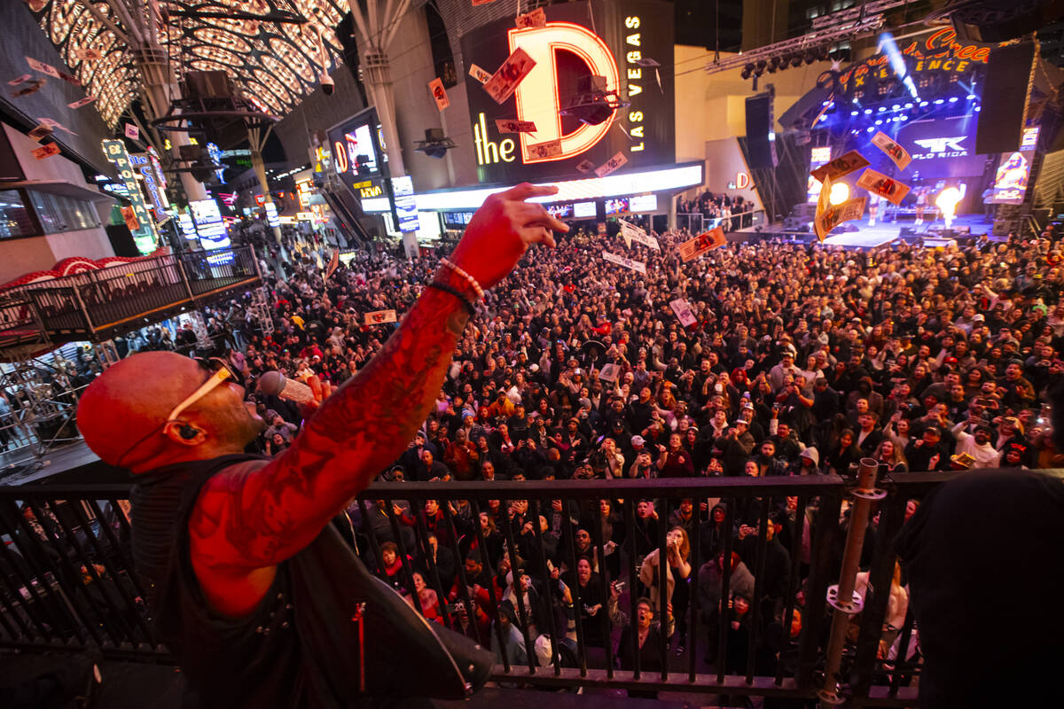 Flo Rida throws fake cash into the crowd while performing from a camera riser during the New Ye ...