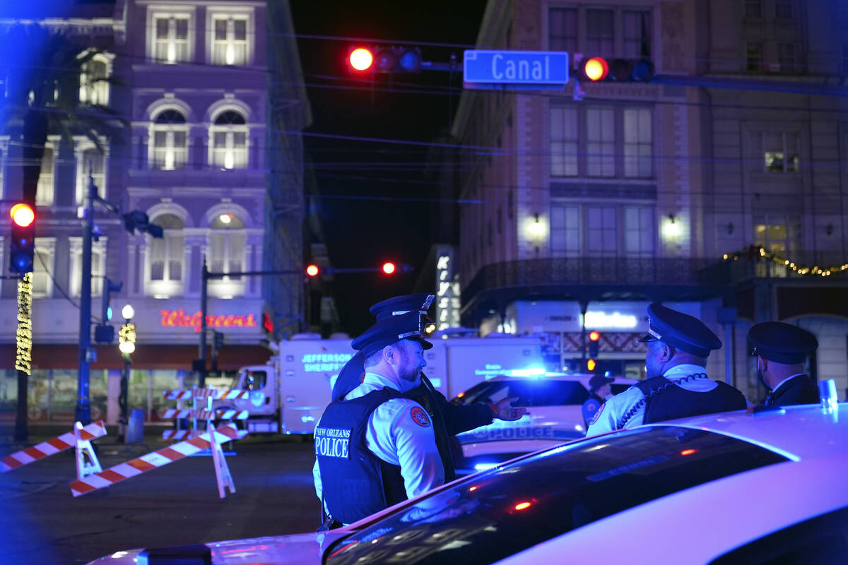 Police officers stand near the scene where a vehicle drove into a crowd on New Orleans' Canal a ...