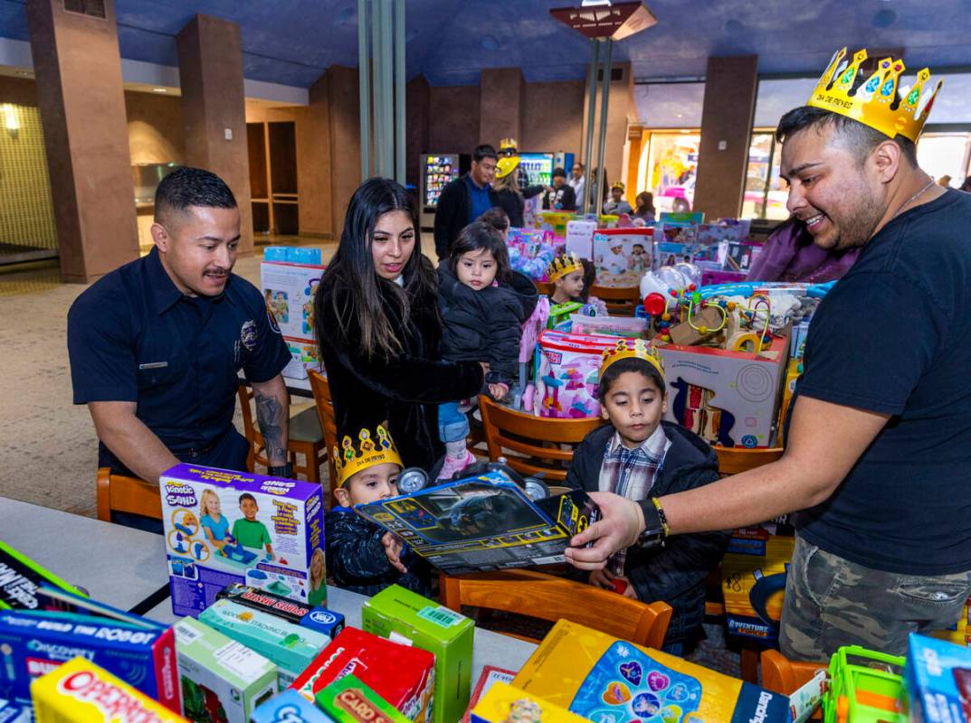 Clark County Firefighter Juan Zelaya, left, joins families as they help find the perfect gift f ...