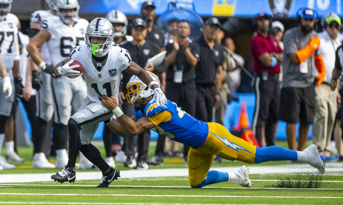 Raiders wide receiver Tre Tucker (11) looks to beat a tackle attempt by Los Angeles Chargers li ...