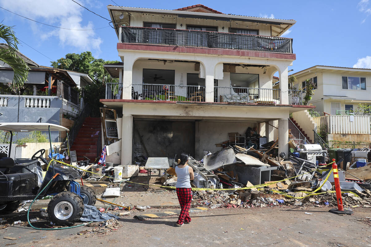 A woman stands in front of the home where a New Year's Eve fireworks explosion killed and injur ...