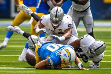 Los Angeles Chargers quarterback Justin Herbert (10) fumbles the ball after a big hit by Raider ...