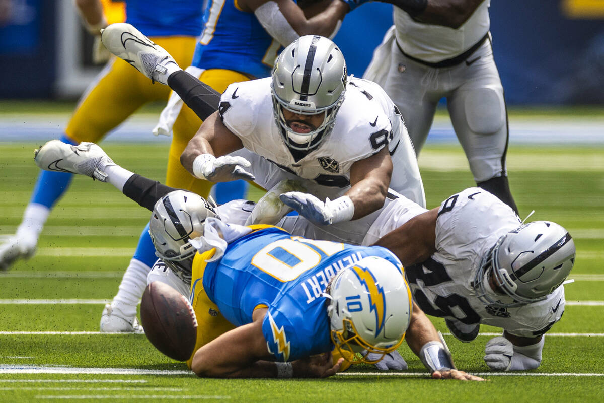 Los Angeles Chargers quarterback Justin Herbert (10) fumbles the ball after a big hit by Raider ...