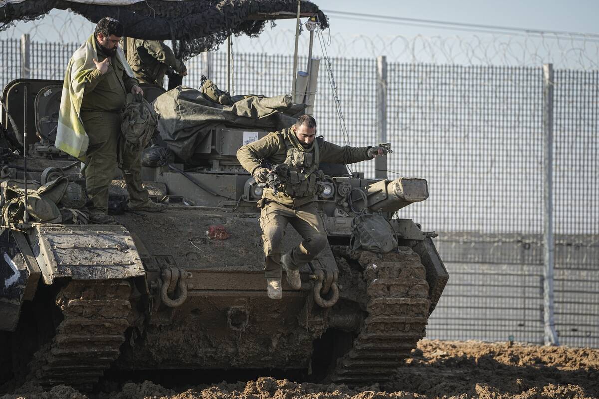 An Israeli soldier jumps off an armoured vehicle at a staging area near the Gaza border in sout ...