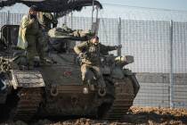 An Israeli soldier jumps off an armoured vehicle at a staging area near the Gaza border in sout ...