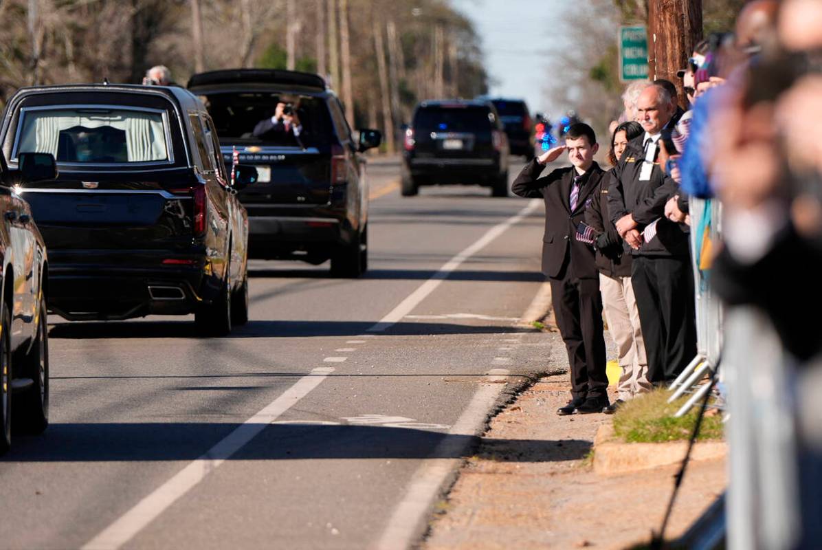 A young boy salutes as the hearse carrying the flag-draped casket of former President Jimmy Car ...