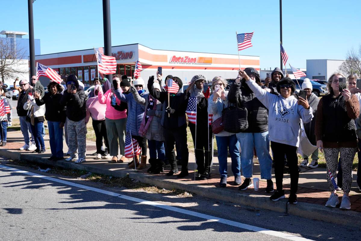 People watch as the hearse containing the casket of former President Jimmy Carter passes throug ...