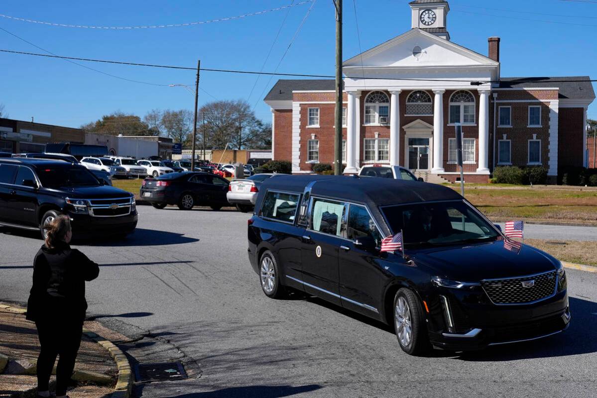 People watch as the hearse containing the casket of former President Jimmy Carter passes throug ...