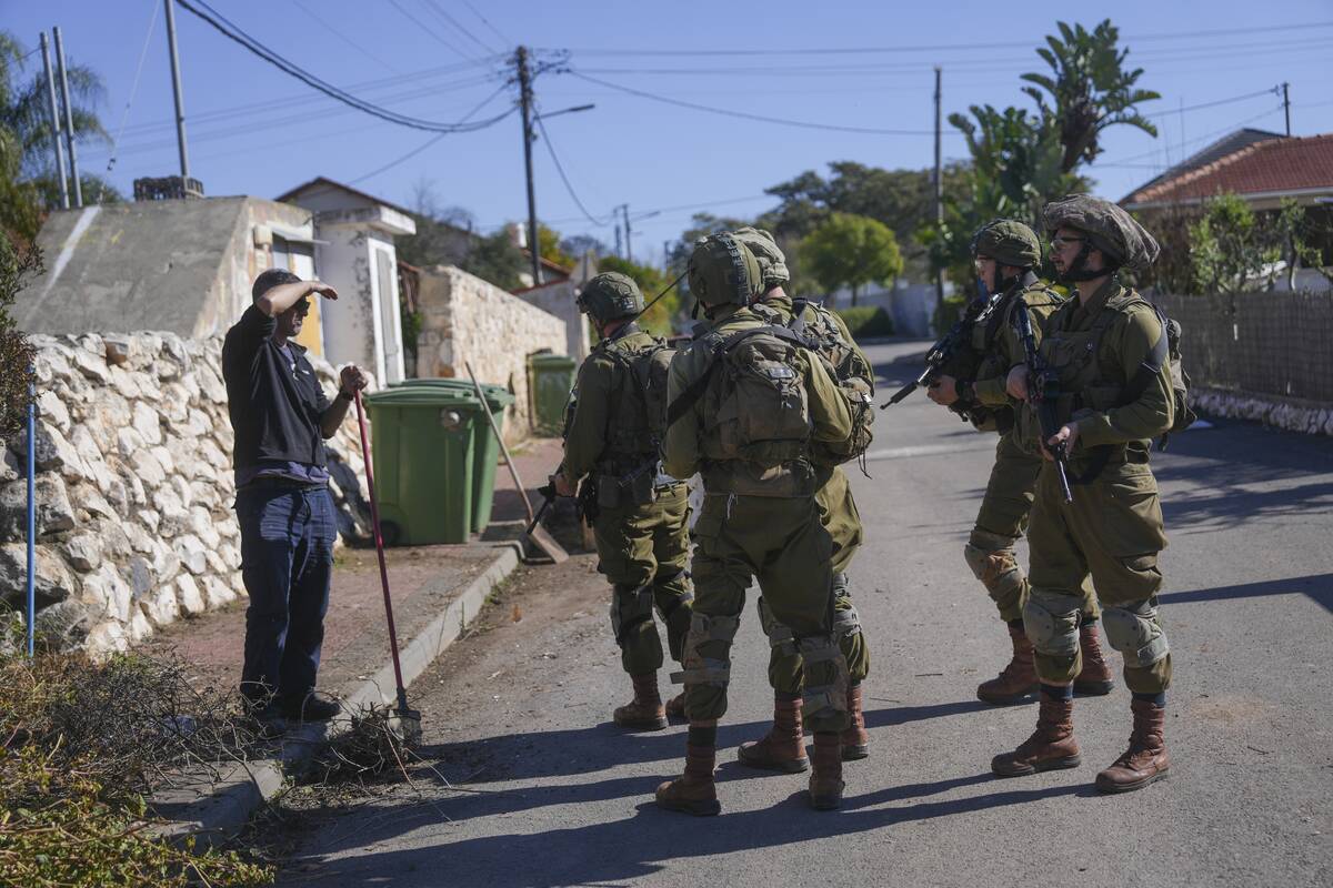 FILE - Rafi Shitrit speaks with soldiers patrolling the area in front of his house in the agric ...