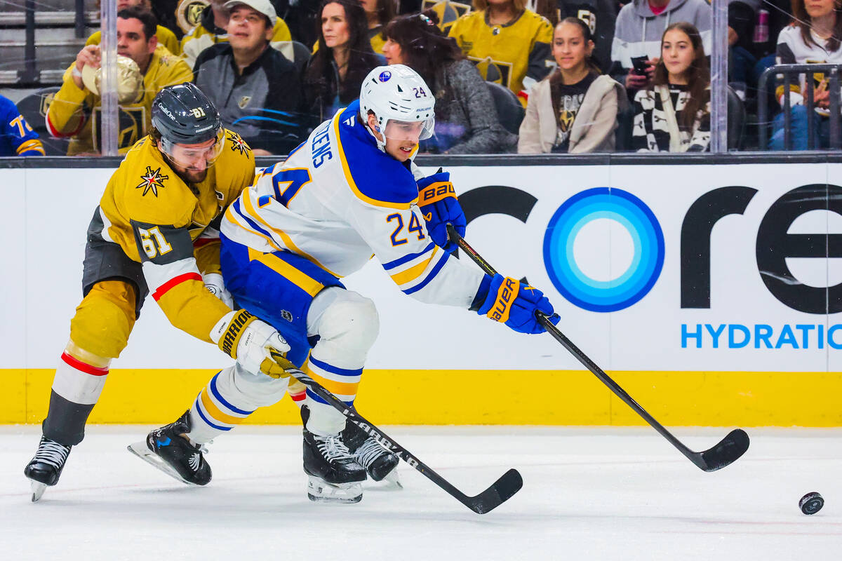 Buffalo Sabres center Dylan Cozens (24) hits the puck away from Golden Knights right wing Mark ...