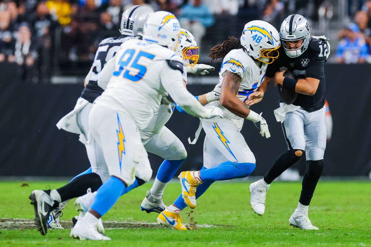 Raiders quarterback Aidan O'Connell (12) runs the ball as Los Angeles Chargers linebacker Bud D ...