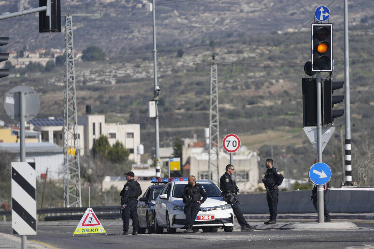 Israeli policemen block a main road after gunmen opened fire on cars and a bus carrying Israeli ...